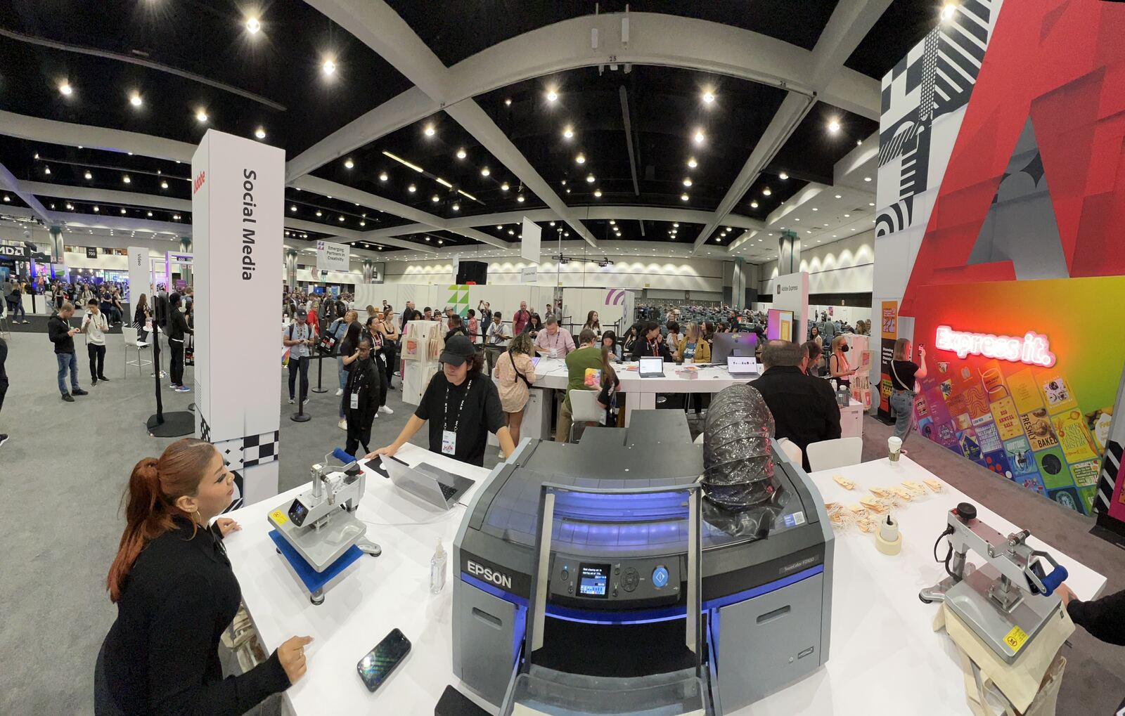 Large indoor festival crowd gathering around event booths and signage under modern venue lighting