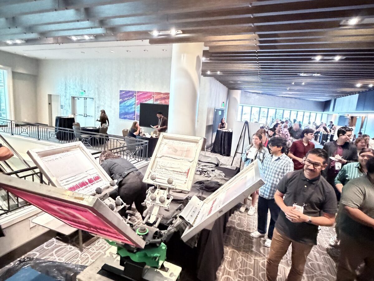 Fans lined up at a live concert merch print station waiting for their shirts