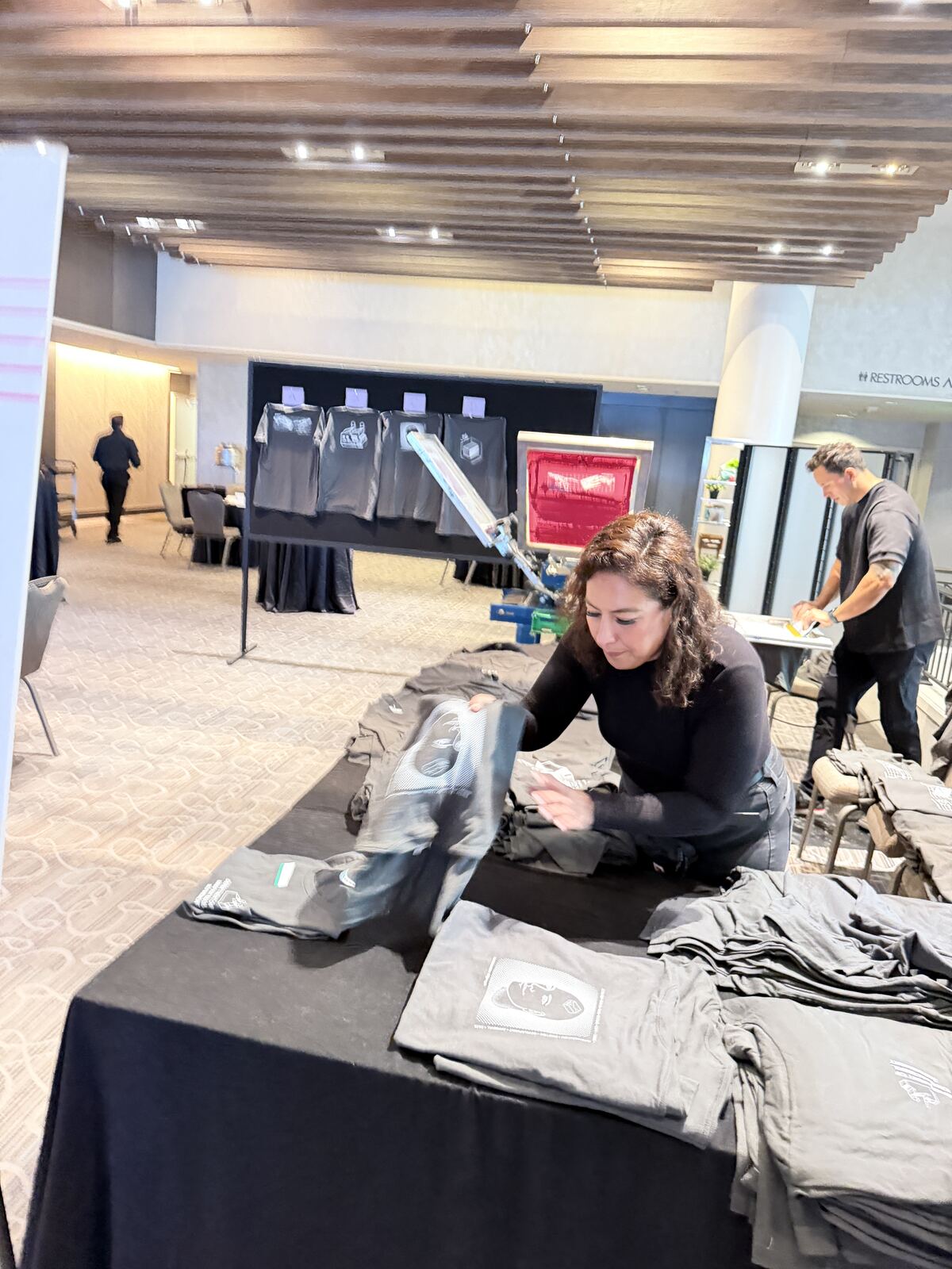 Event attendees and staff at a festival booth with apparel displays